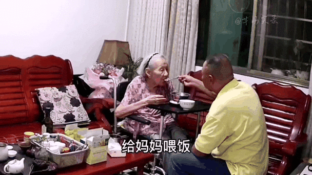 父亲一手扶着母亲一手给母亲喂饭